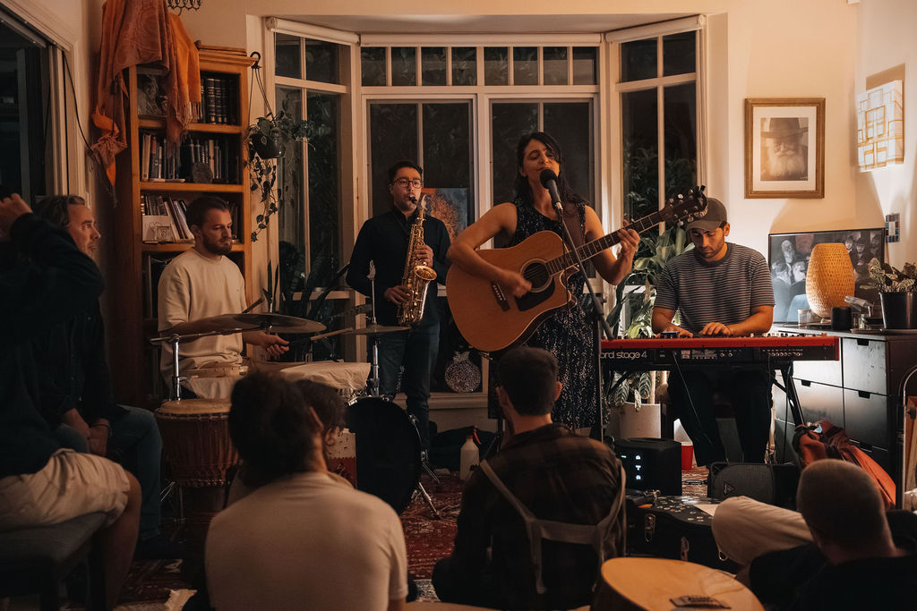 the house band and a singer playing to a crowd on the floor at the salon